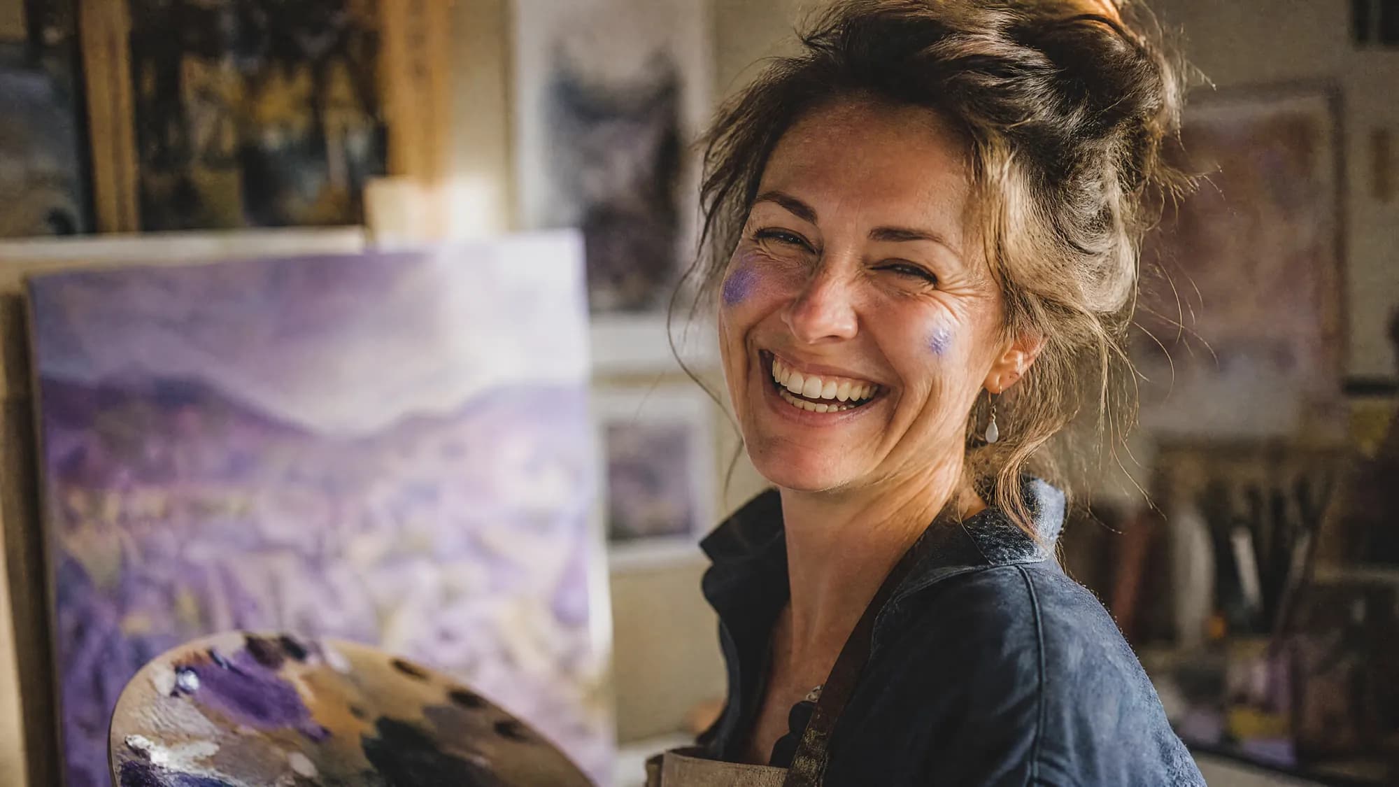 Peintre souriante devant sa palette dans son atelier